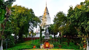 Ein Tempel mit einer zentralen Stupa, umgeben von einem kreisförmigen Garten und einer Statue im Vordergrund.