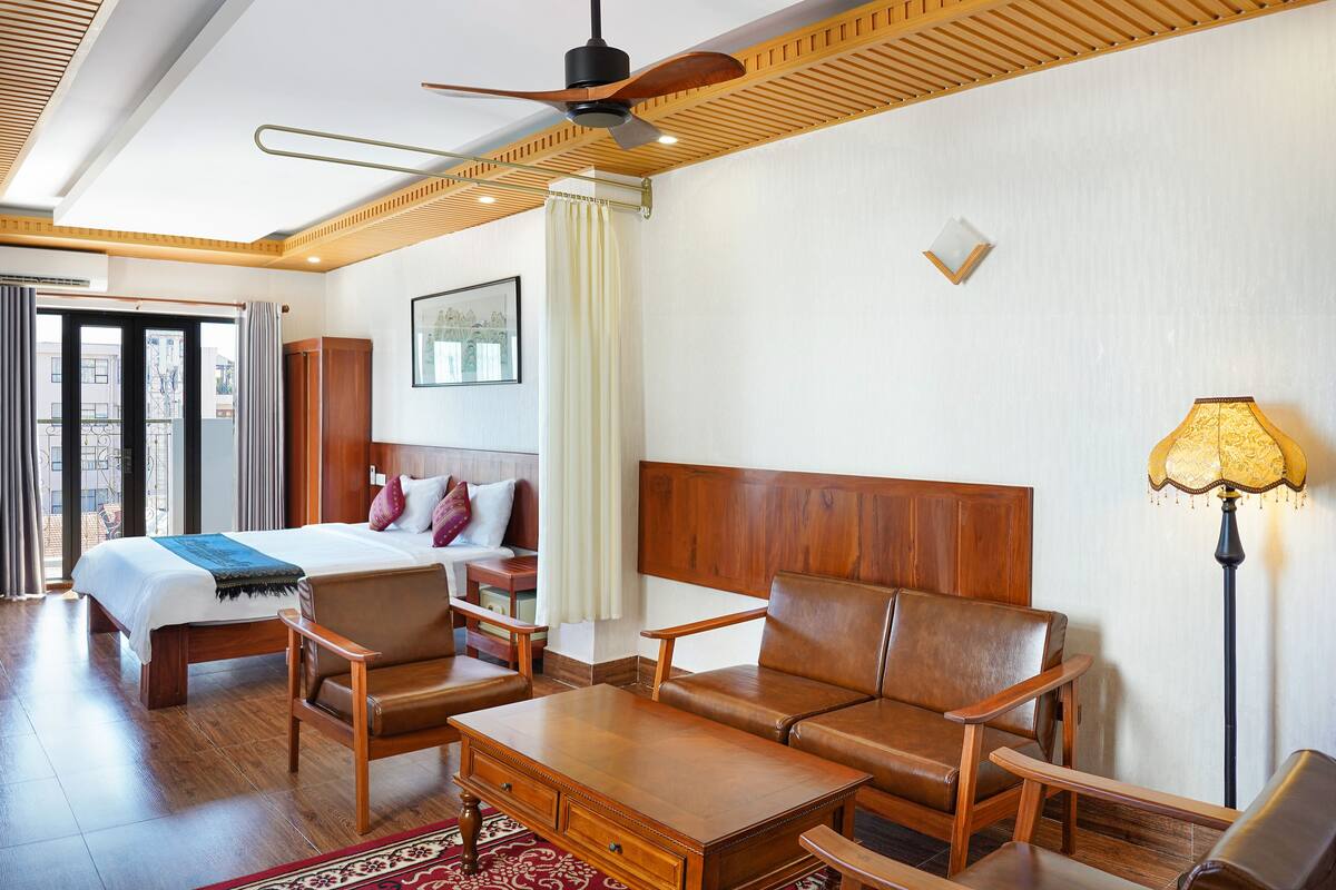 Una habitación de hotel con cama, sofá, mesa de centro y lámpara de pie.