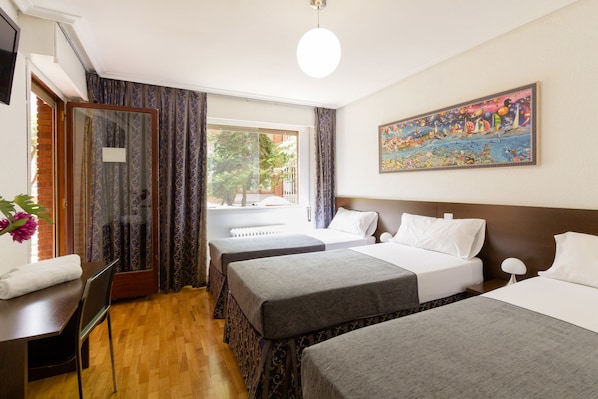 A hotel room with two beds, a desk with a chair, a TV, and a painting on the wall.