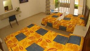 A hotel room with two beds, a desk, a chair, a TV, and a window with curtains. - Hotel Rio Balsas (Manzanillo)