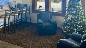 A cozy room with a large window, a decorated Christmas tree, and a desk with chairs.
