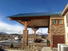 A building with a covered entrance, stone pillars, and a metal roof.