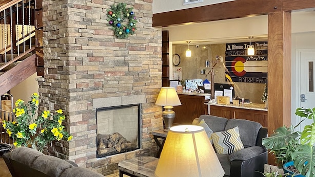 A spacious lobby with a stone fireplace, comfortable seating, a staircase, and a reception area.