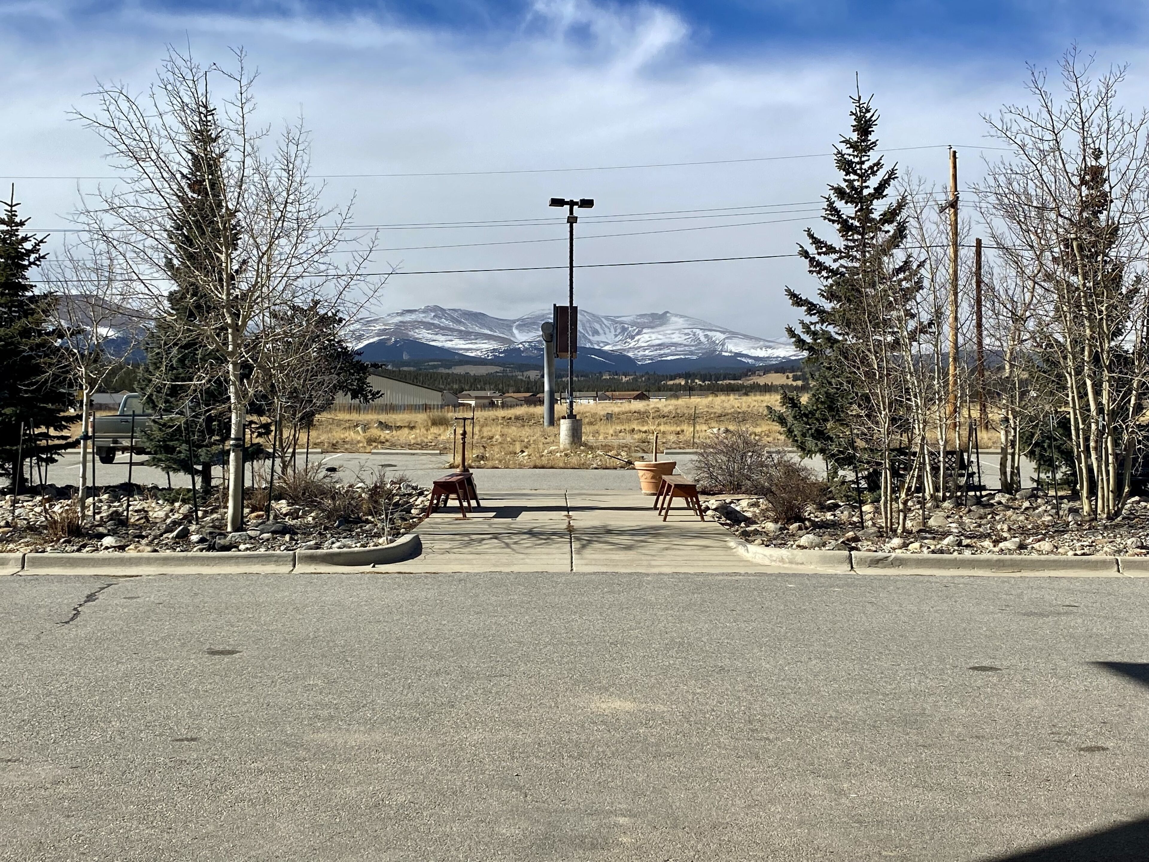 A parking lot with a mountain view, a street lamp, and a few trees.