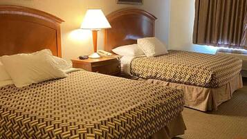Dos camas individuales con ropa de cama estampada, una lámpara de noche, un teléfono y una ventana con cortinas.