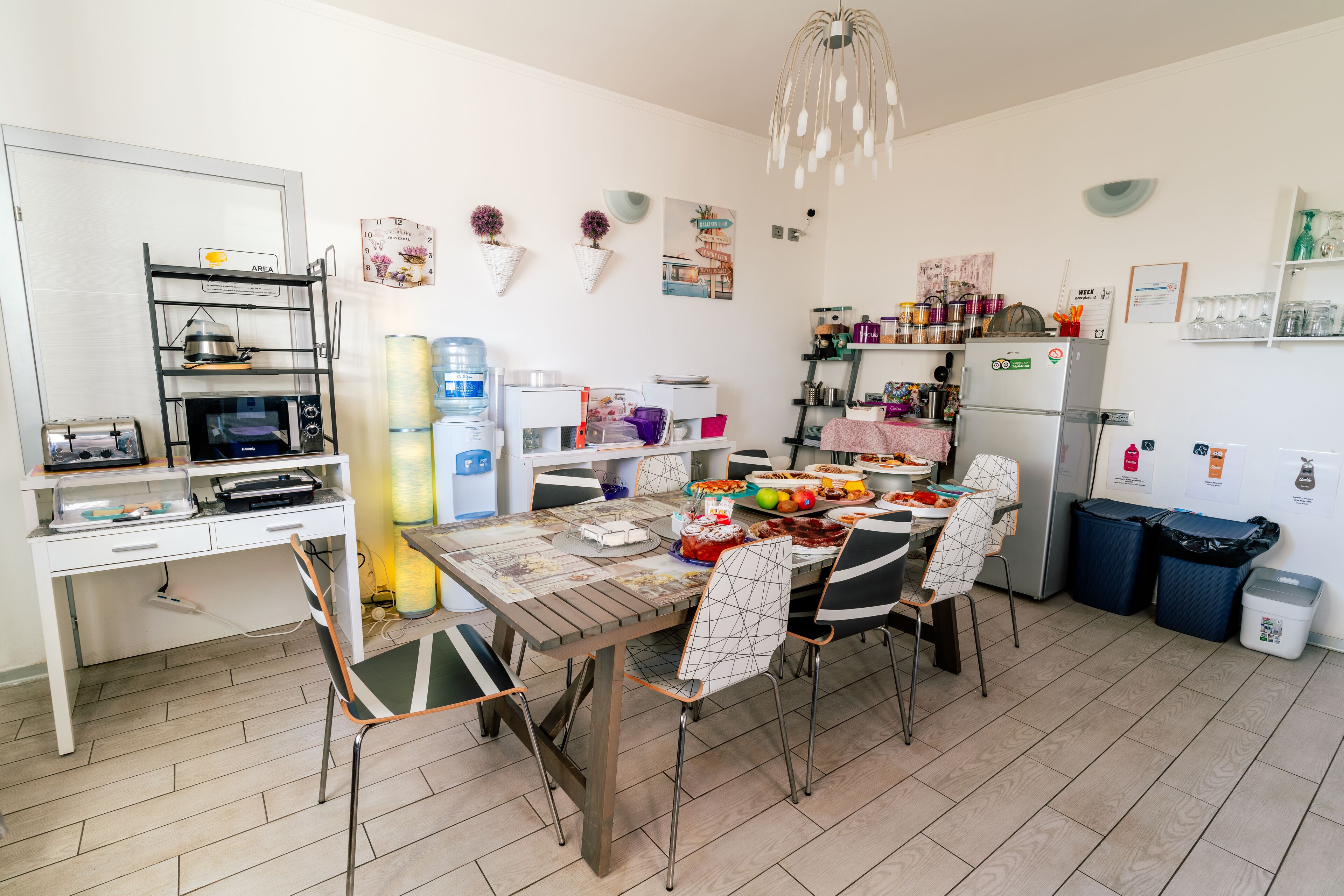 Cocina compacta con mesa, sillas, microondas, refrigerador y diversos utensilios.
