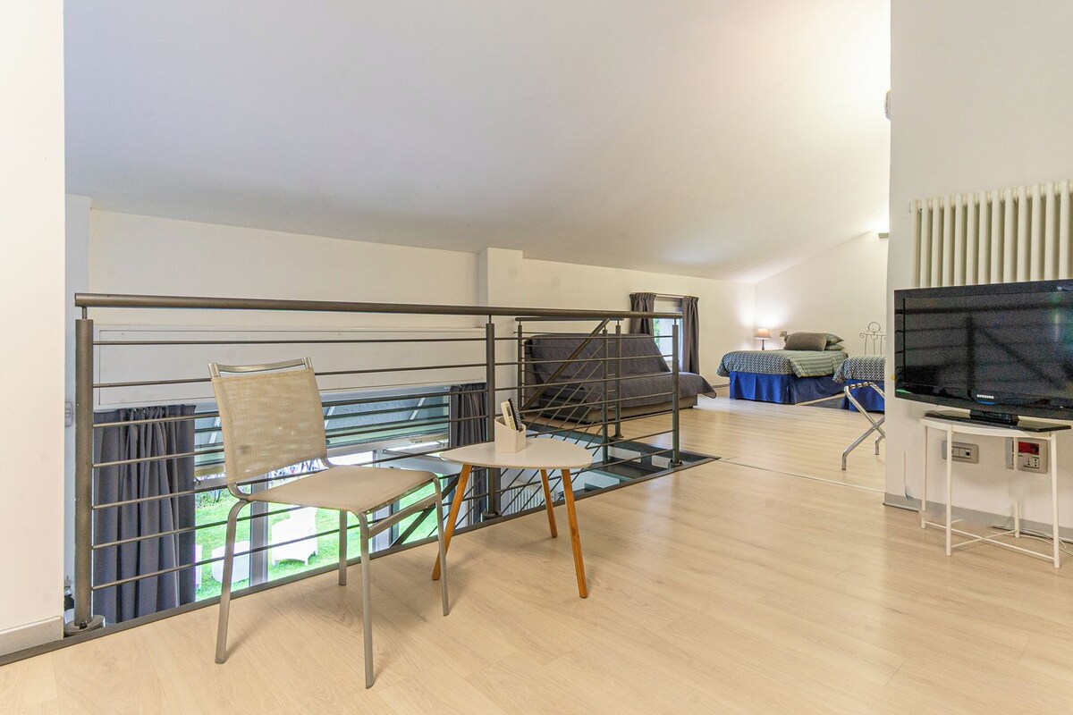 A room with a balcony, a bed, a television, and a chair.