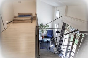 A bedroom with a bed, a chair, a small table, and a staircase leading to another room. - Il Giardino di Rebecca (Ferrara)