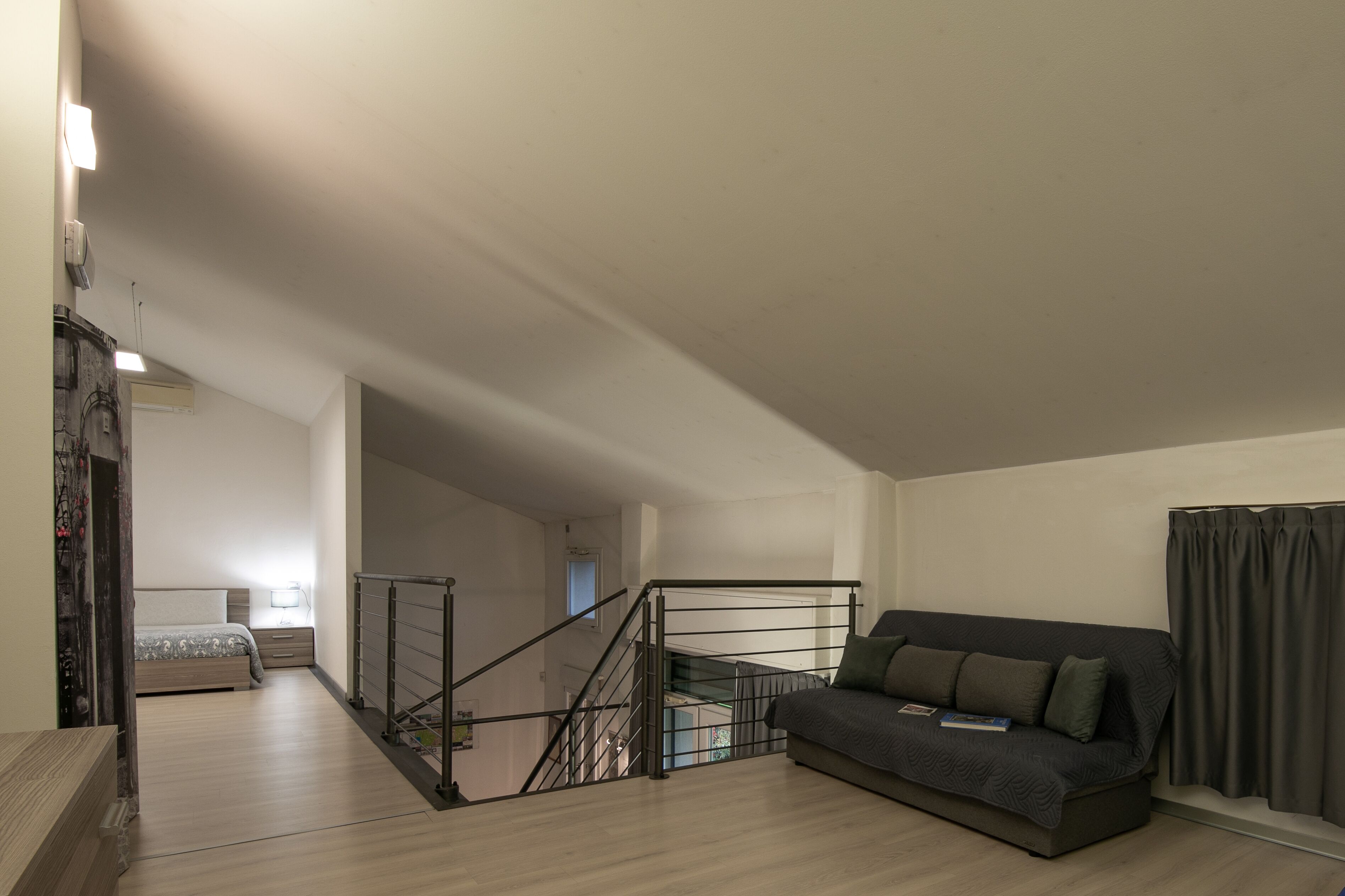 Un salon moderne avec un canapé, un escalier et un lit en arrière-plan.