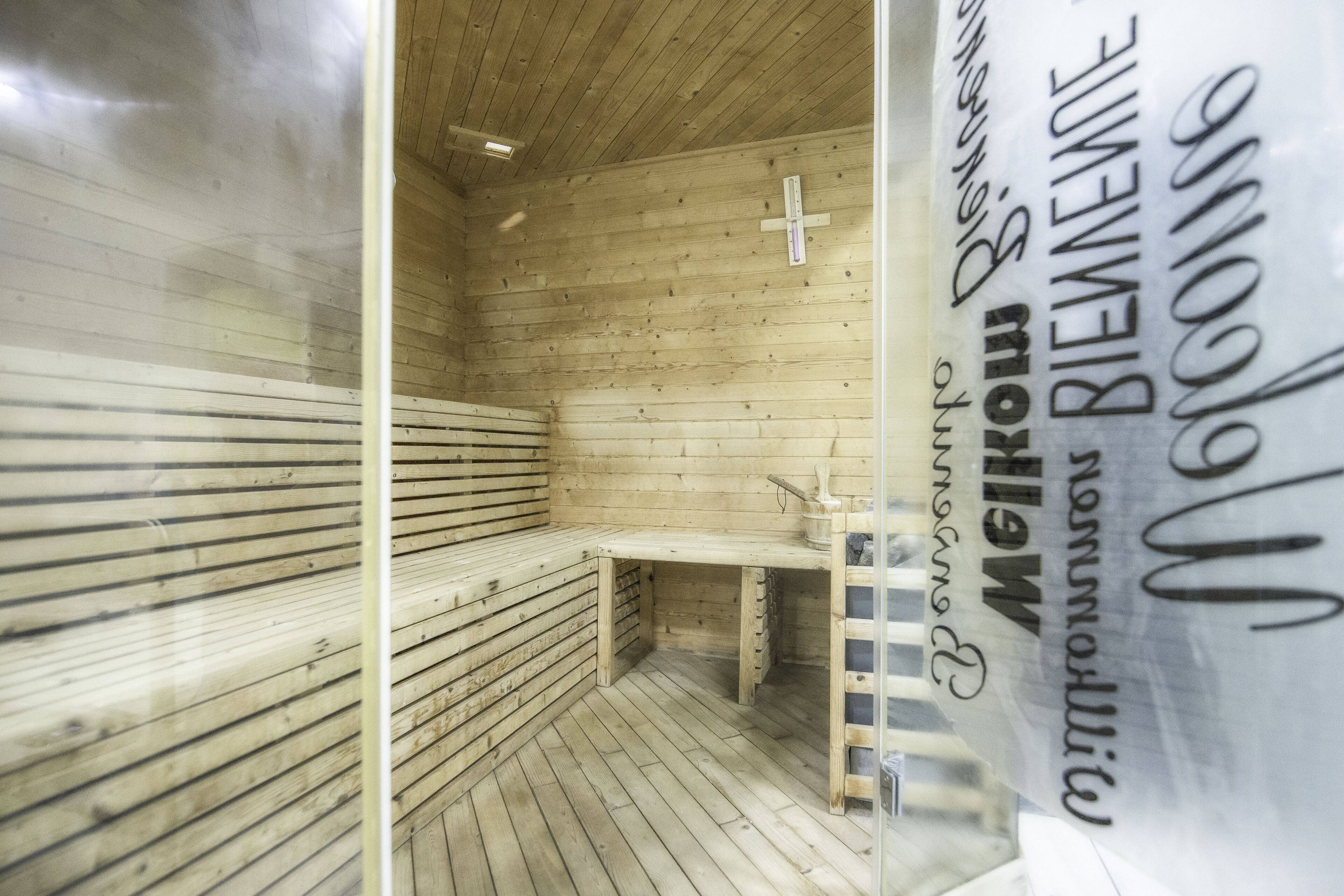 Una sauna con panche in legno e una panca con portasci.
