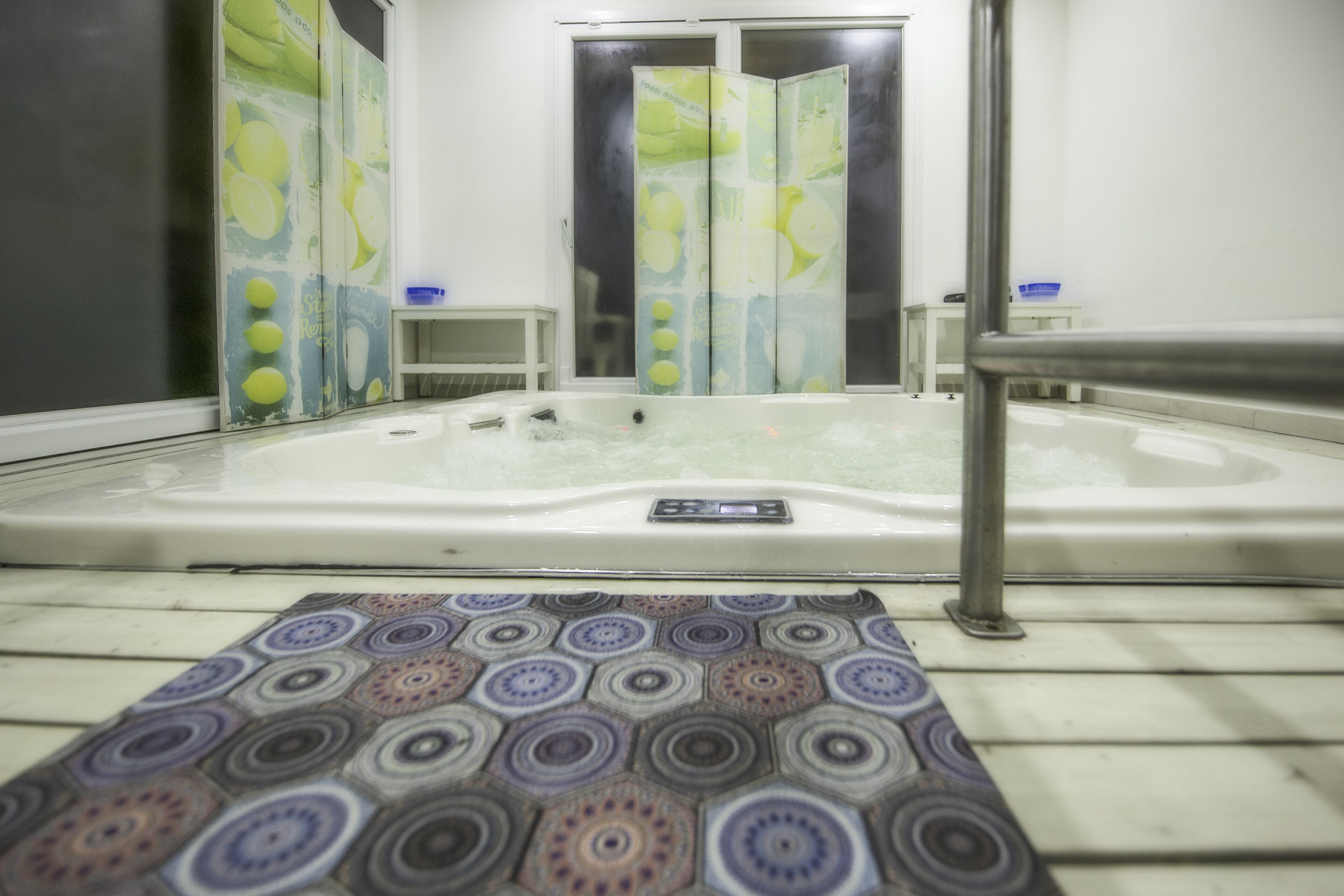A bathroom with a bathtub, a shower area, and a patterned mat on the floor.