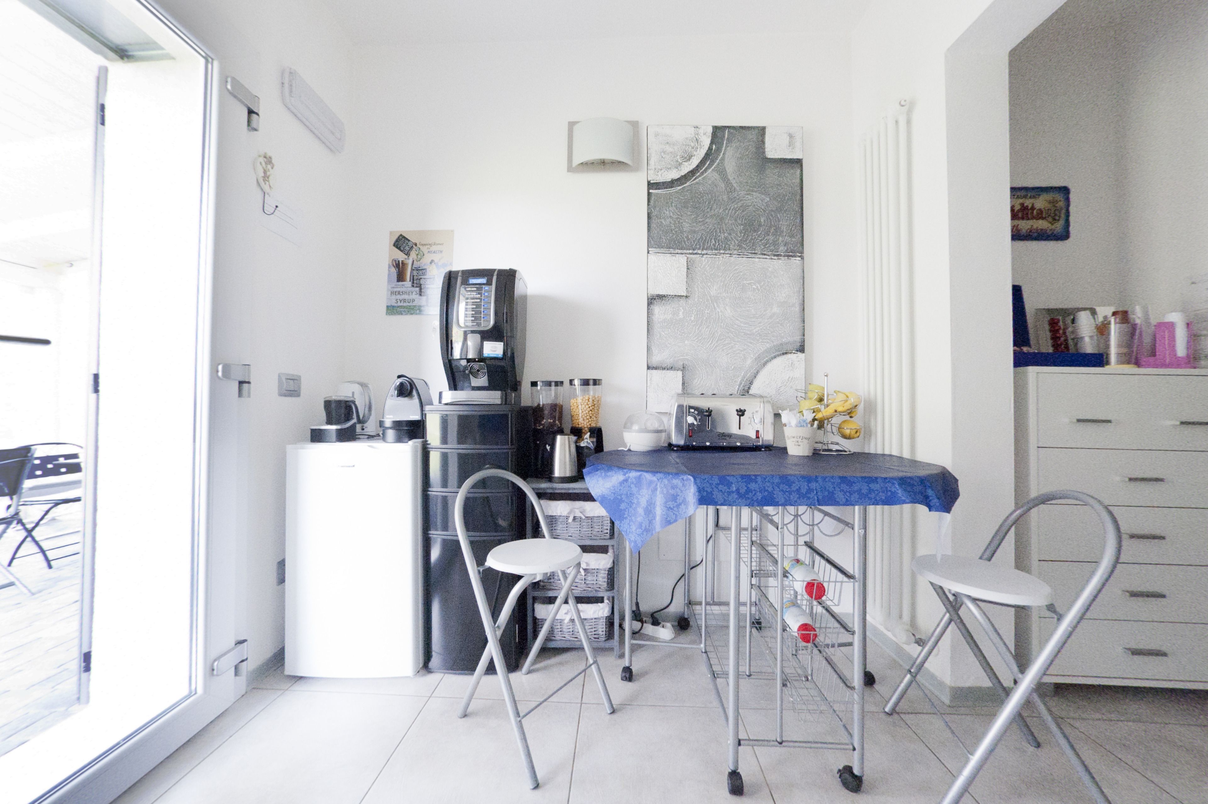 A compact kitchen with a coffee machine, a sink, and a small dining area with a table and chairs.