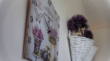 A wall clock with floral designs and a wicker basket with purple flowers.