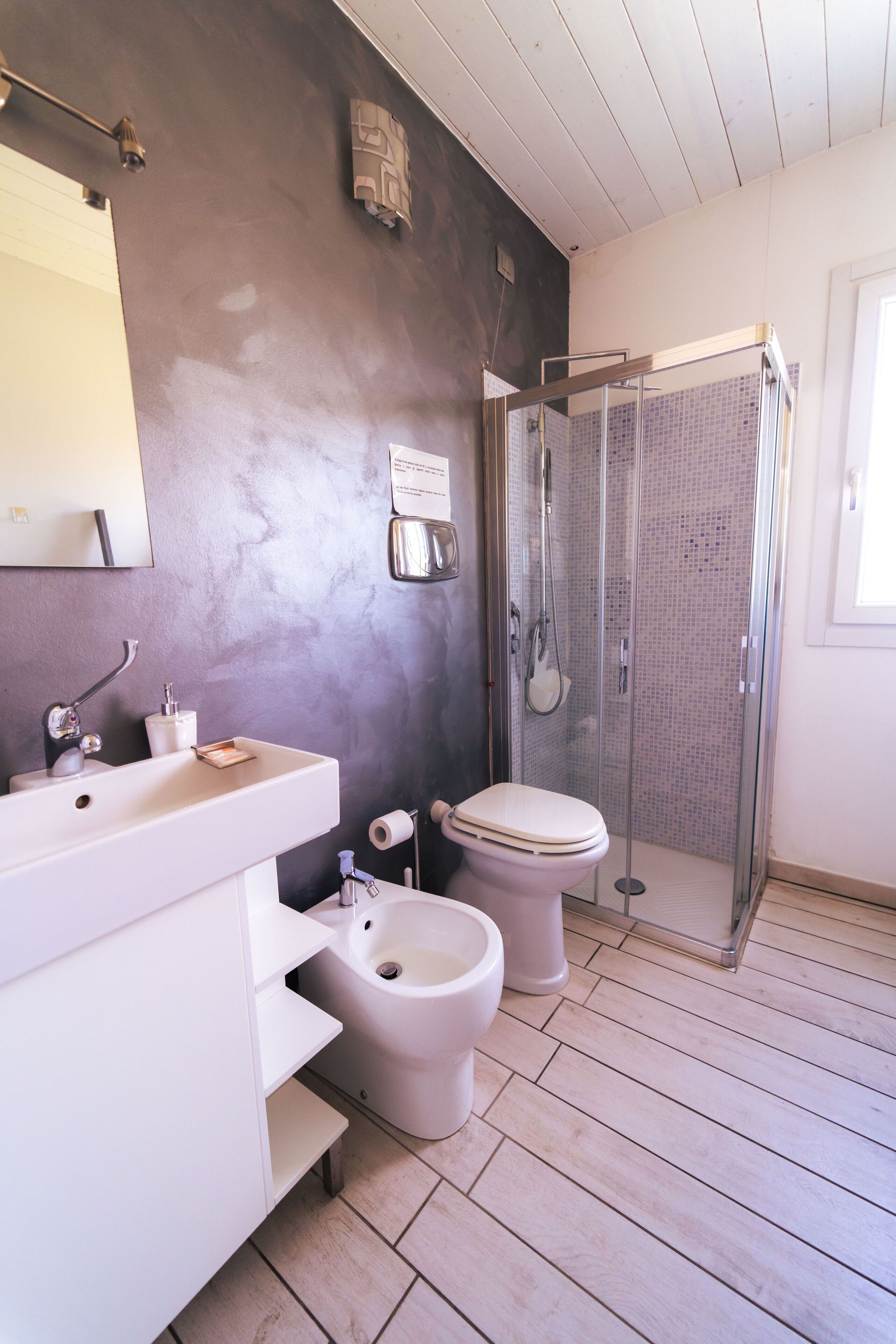 Ein Badezimmer mit Waschbecken, Toilette, Bidet und einer Duschkabine.