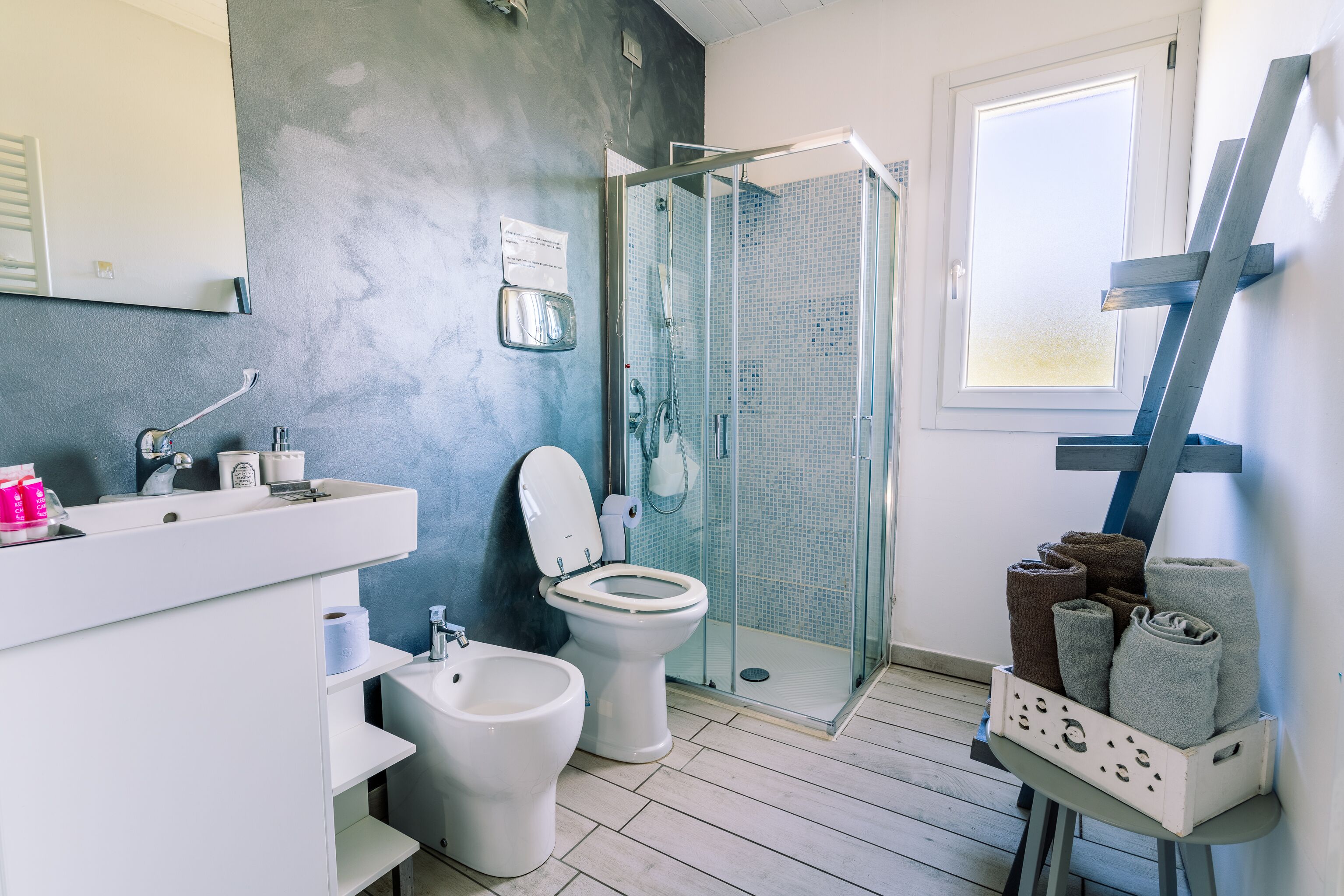 Un baño moderno con cabina de ducha de vidrio, un lavabo blanco y un inodoro.
