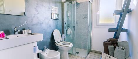 Un baño moderno con cabina de ducha de vidrio, un lavabo blanco y un inodoro.