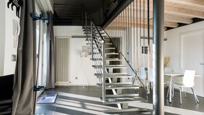 Un interior moderno con una escalera, una mesa de vidrio y una silla blanca.
