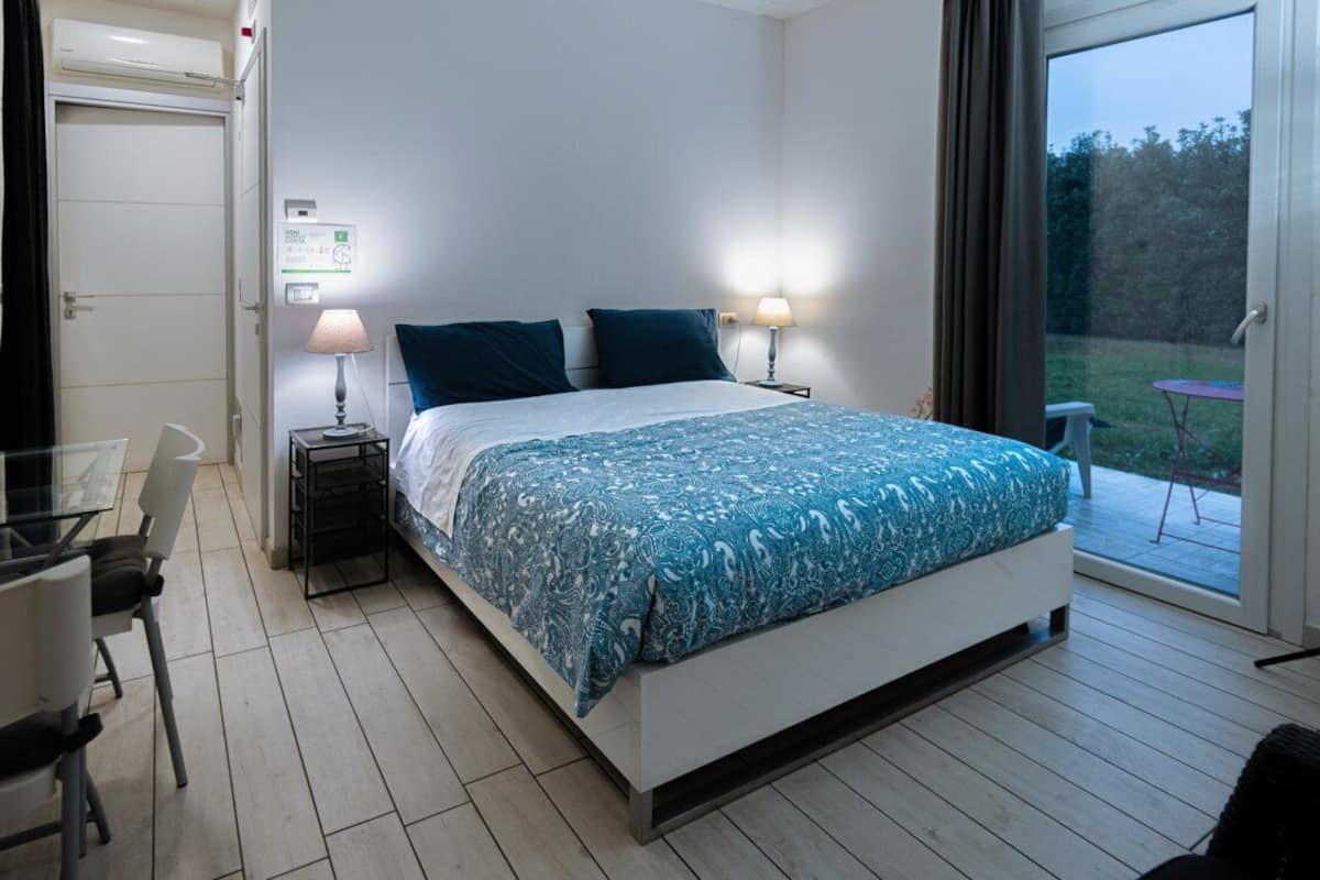A bedroom with a bed, bedside lamps, a table, and a chair.