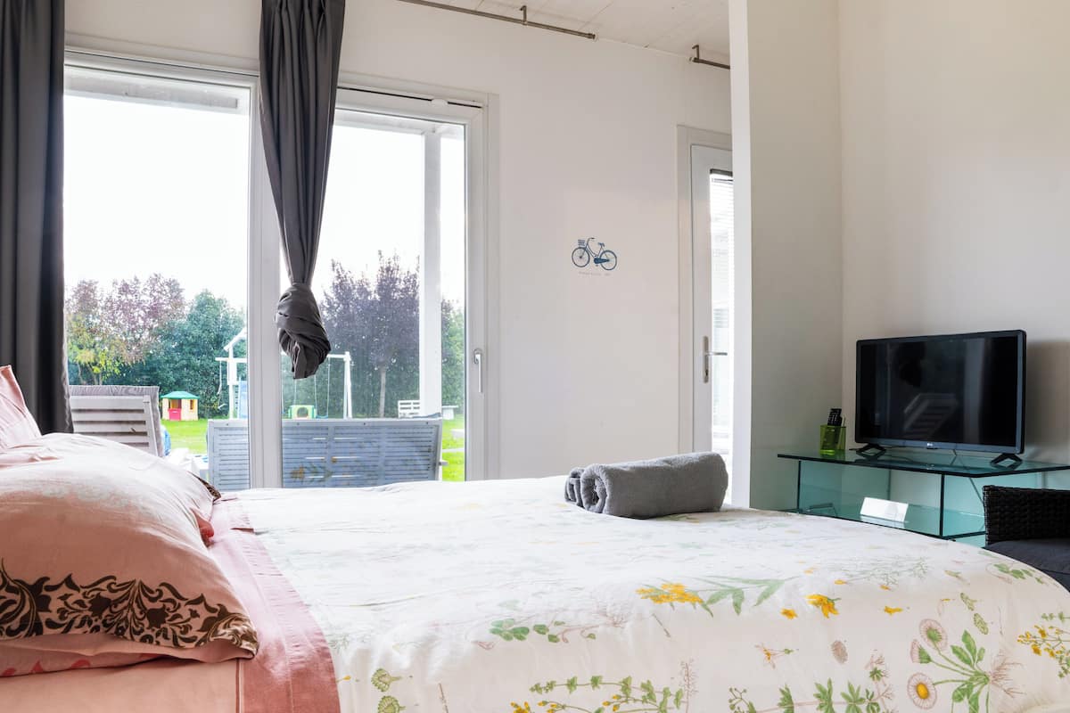 A bedroom with a bed, a TV, and a view of the outdoors.