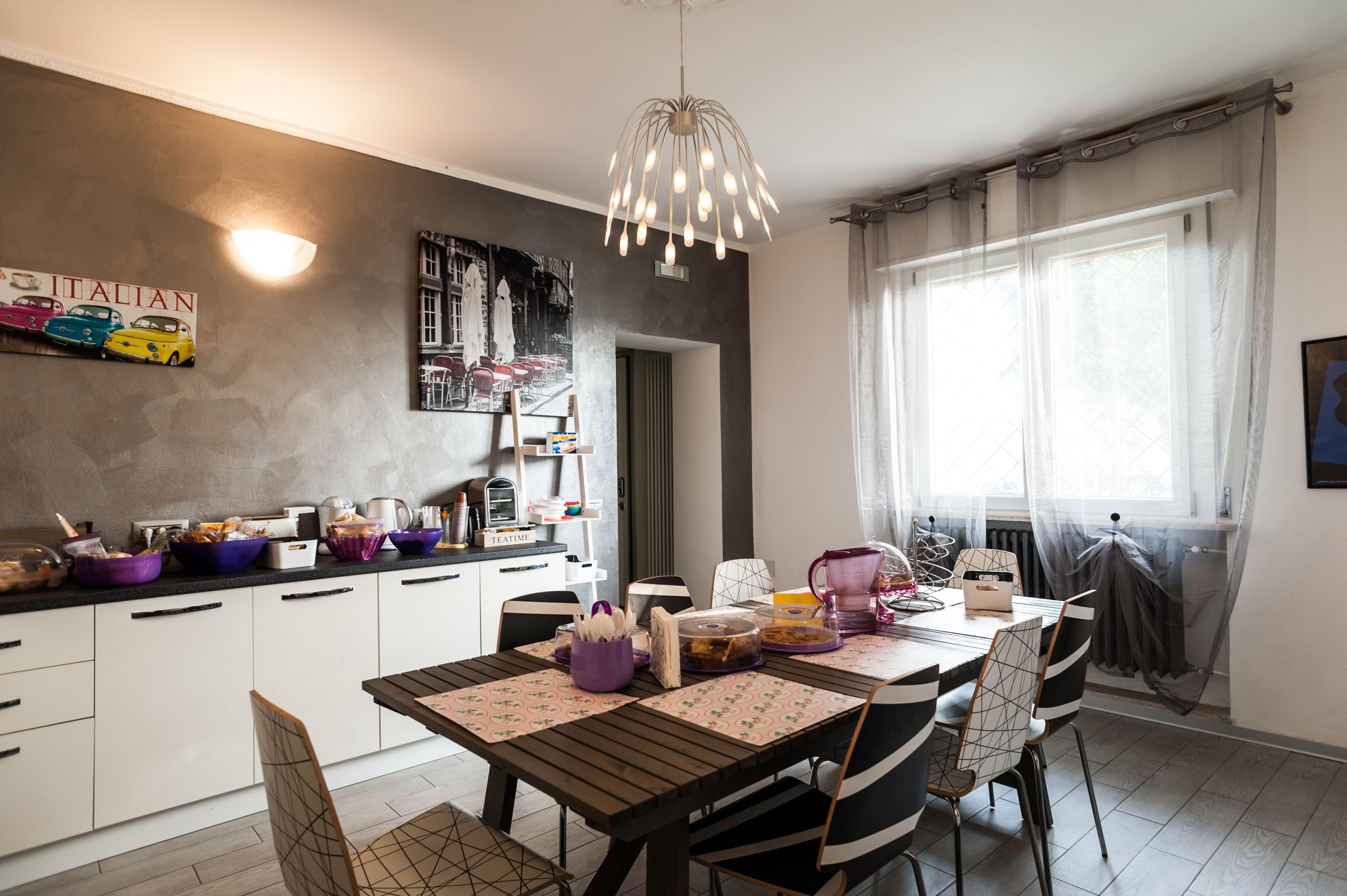 Een moderne keuken met witte kasten, een eettafel met zwart-witte stoelen en een hanglamp.