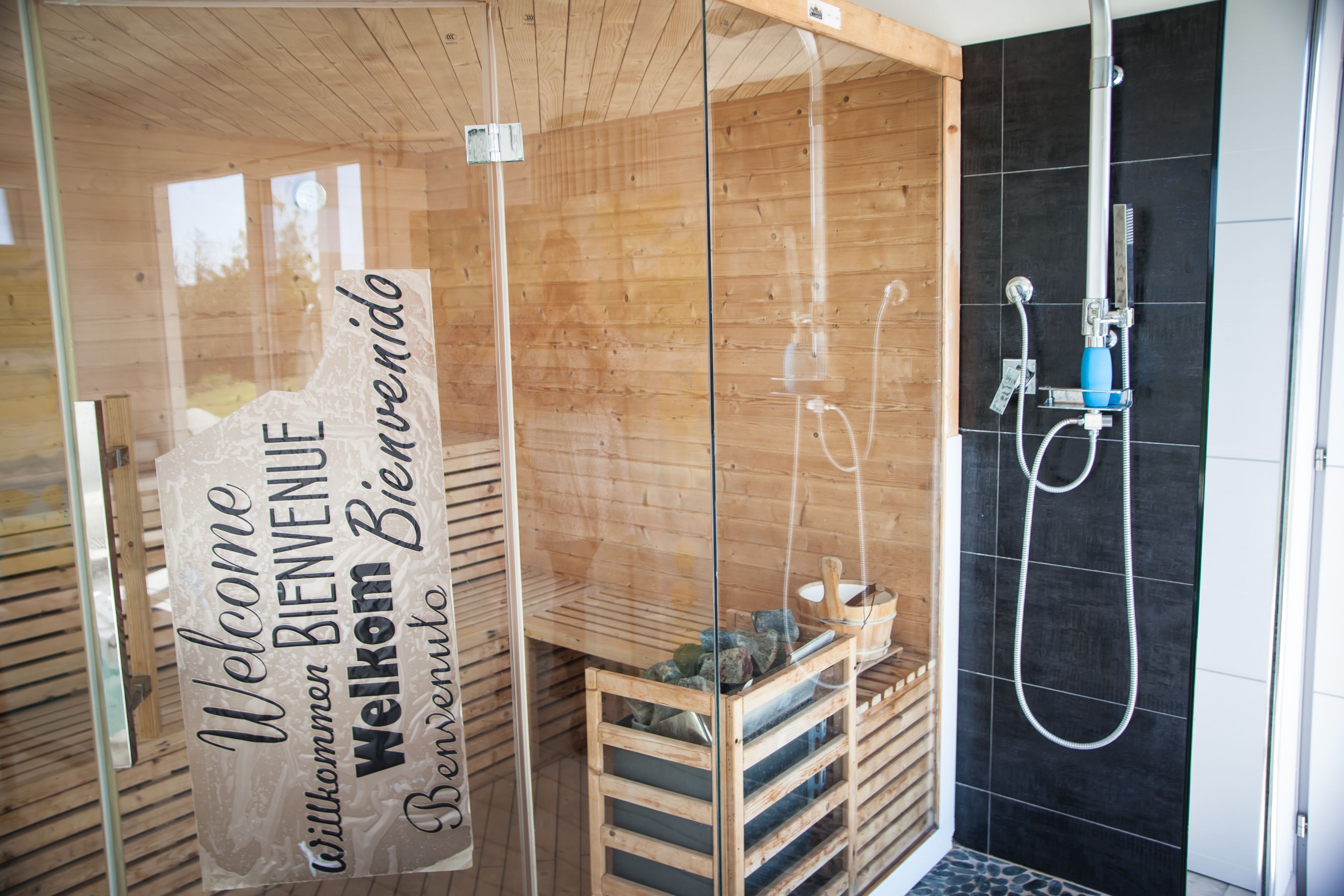 Aseo con cabina de madera, puerta de cristal y ducha.