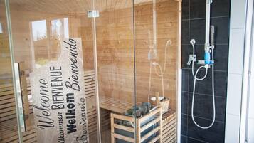 Aseo con cabina de madera, puerta de cristal y ducha.