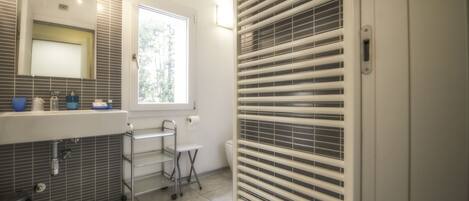 A modern bathroom with a large mirror, a sink with a chrome faucet, a window, and a toilet.