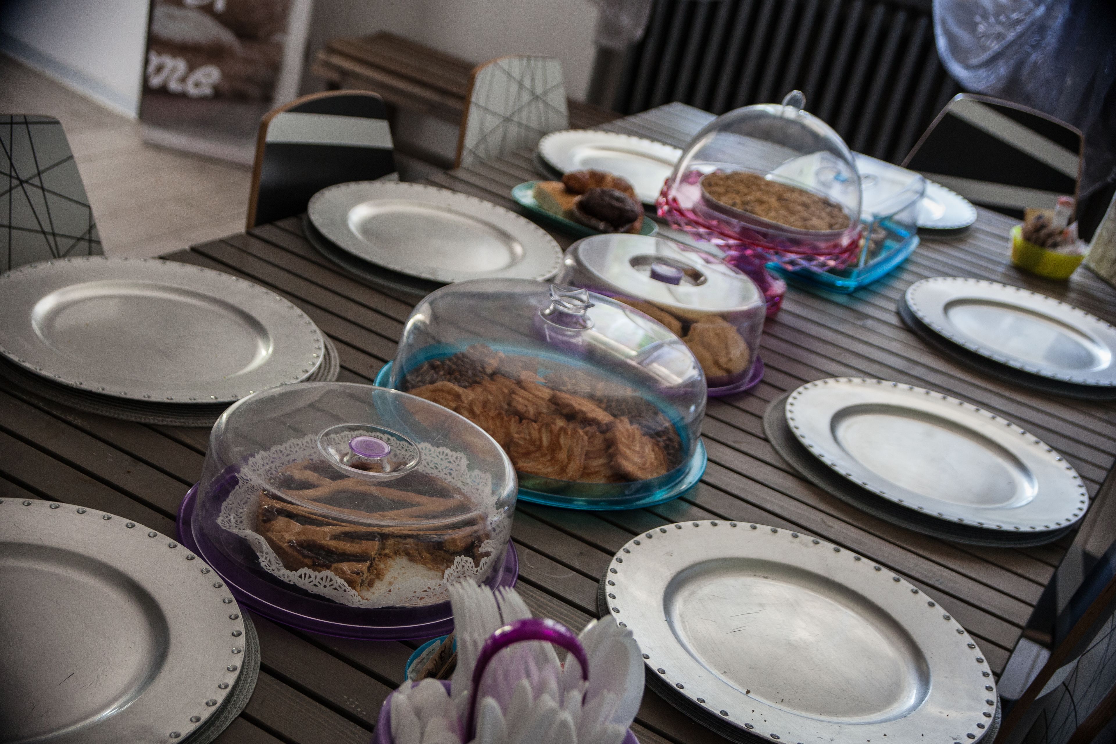 Een gedekte eettafel met borden, kommen en bedekte gerechten.