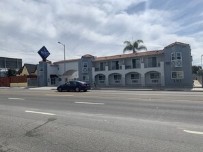 A motel with a two-story building, a car parked in front, and a clear sky. - Crescent Inn (Wilmington)