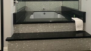 Un baño moderno con un espejo grande, un lavabo negro y un revestimiento de azulejos.