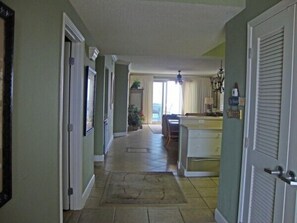A hallway leading to a kitchen with a dining area.