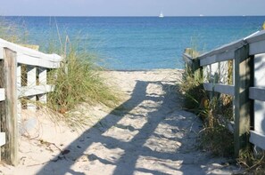 A sandy beach path leading to the ocean with a wooden fence on one side. - Tern Key Realty & Rentals (Pensacola)