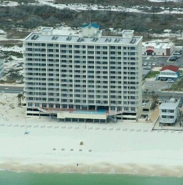 A large hotel with multiple floors, a swimming pool, and a beach in the foreground. - Tern Key Realty & Rentals (Pensacola)