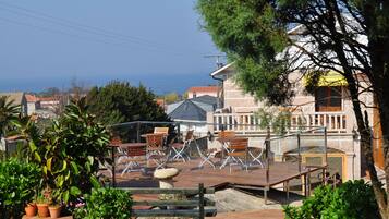 Une terrasse avec des places assises extérieures, un bâtiment en pierre et une vue sur la mer.