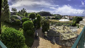 Un jardín con terraza de madera, sendero de piedra y diversas plantas.