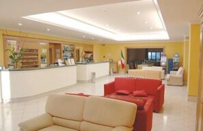 A hotel lobby with a reception desk, a red sofa, and a white sofa. - Hotel Valentino (Sora)