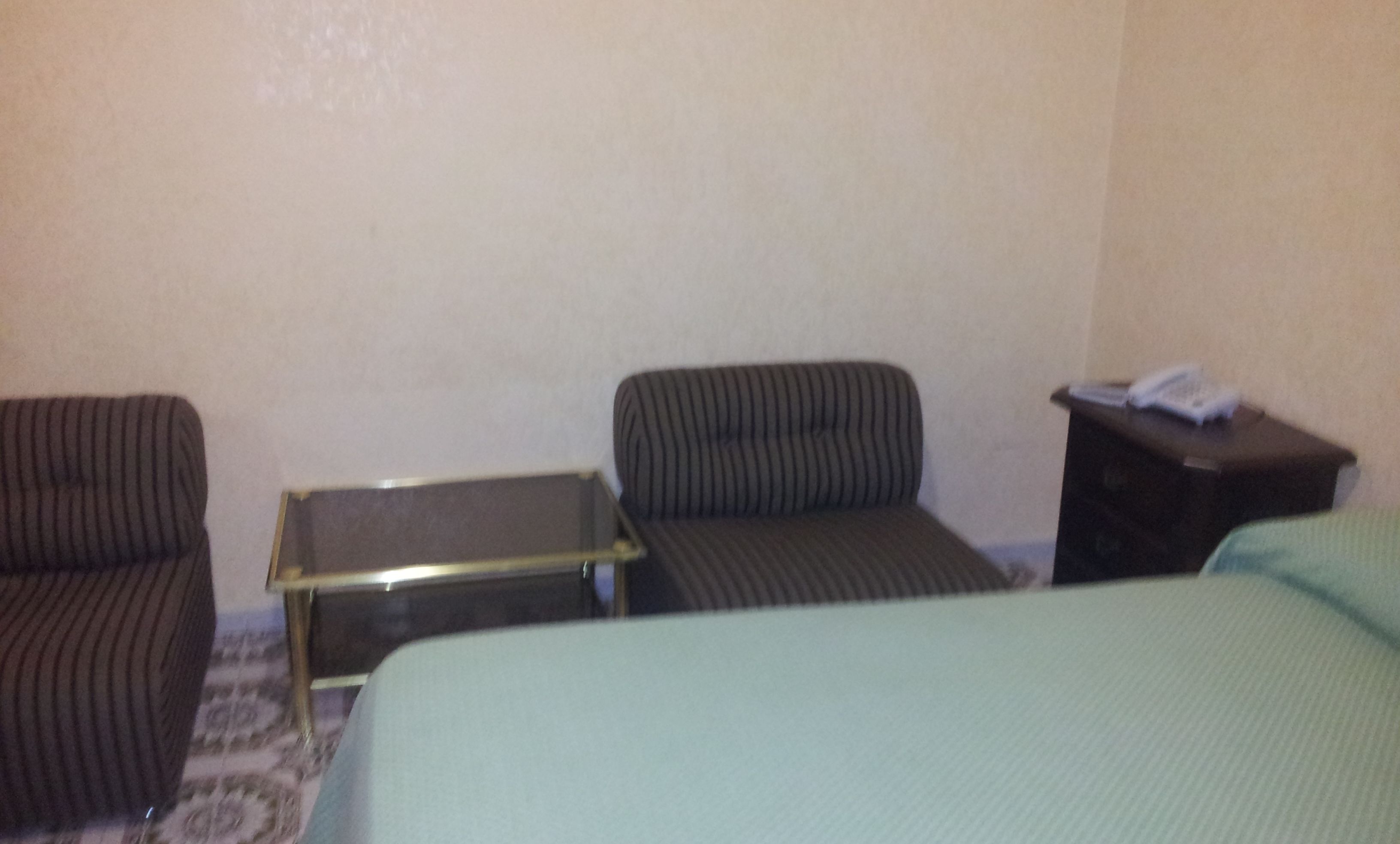 A hotel room with a bed, two chairs, a small table, and a nightstand with a telephone.