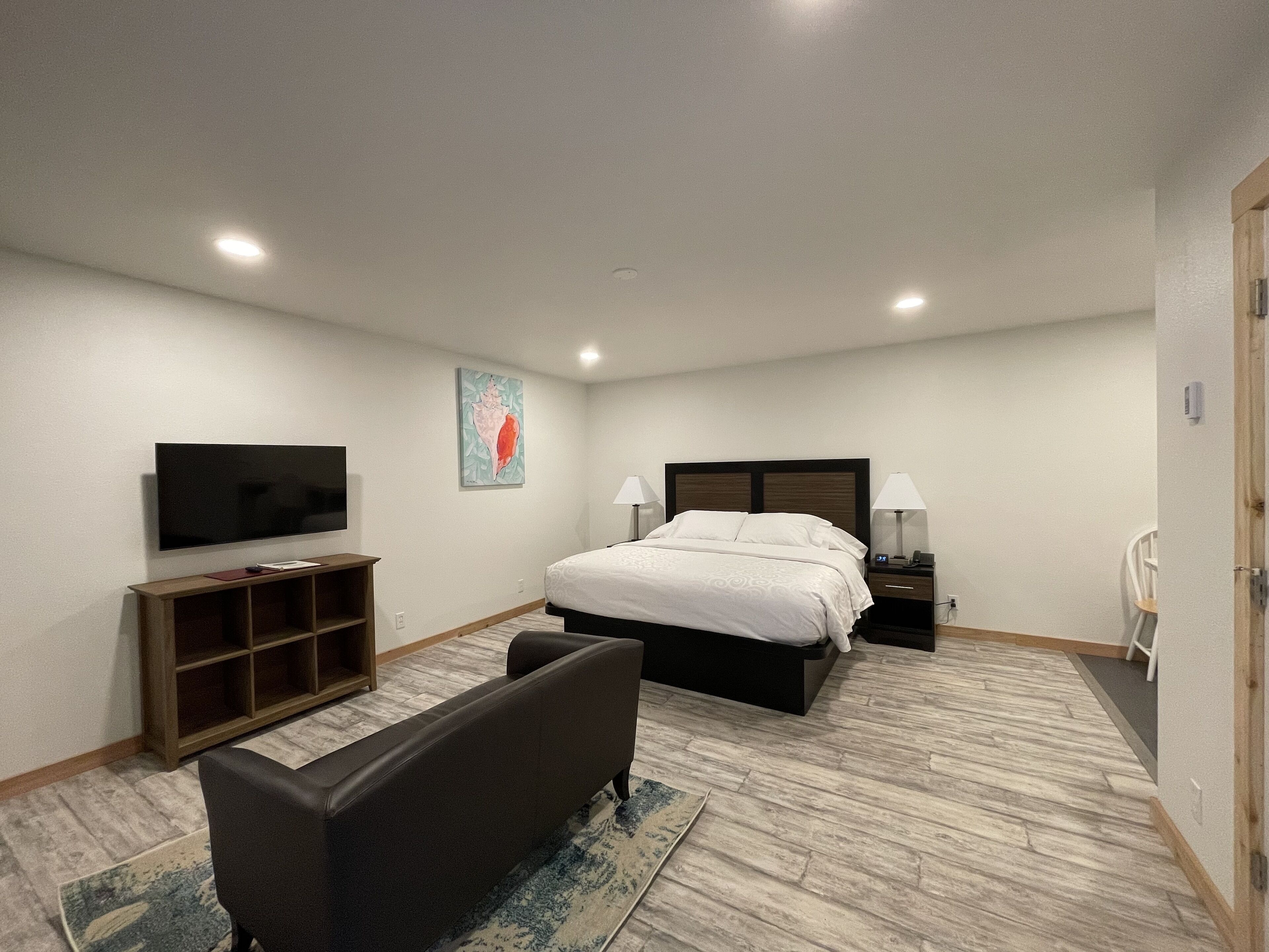 A hotel room with a bed, a TV, a desk, and a chair.