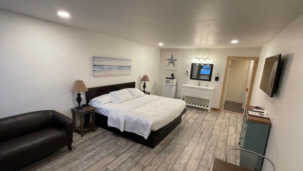 A bedroom with a bed, bedside tables, a TV, and a desk. - The Inn at Old Town (Bandon)