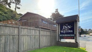 A wooden fence, a building with a balcony, and a sign for 'The Inn at Old Town' with a message 'rest, rise & relax here'. - The Inn at Old Town (Bandon)
