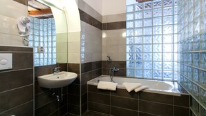 Un baño con lavamanos, espejo, ducha y bañera.