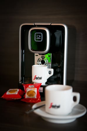 Máquina de café com uma chávena e dois sachês de café.