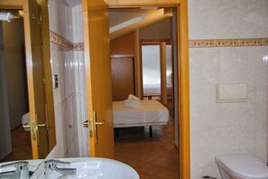 A hotel room with a bathroom, a bed with a white bedspread, and a toilet. - Apartamentos Soldeu Luxury 3000 (Bordes d'Envalira)