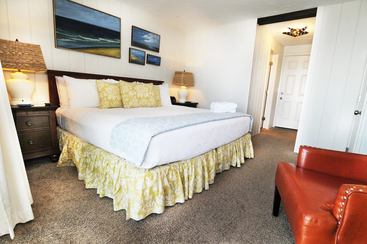A neatly made bed with a white and blue bedspread, flanked by two bedside lamps and a nightstand with a lamp.