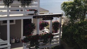 A white building with a sign reading "DYER'S BEACH HOUSE MOTEL" and a view of the sea with boats.