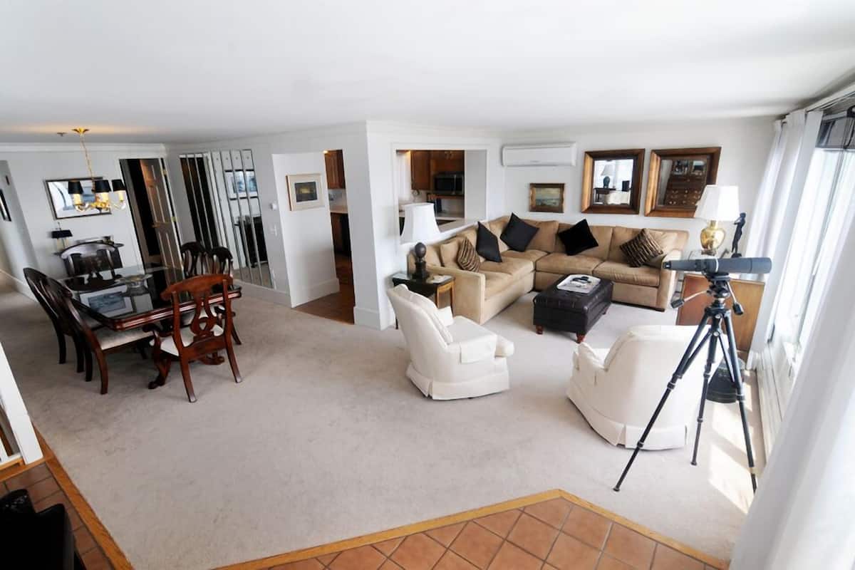 A spacious living room with a dining area, a sofa set, and a tripod.