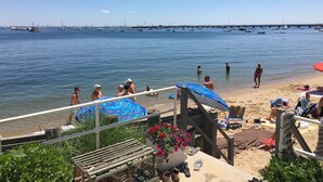 A beach with a wooden deck, a lifeguard tower, and a view of boats in the water.