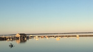 A calm harbor with boats docked at piers, a large building with a dome, and a clear sky.