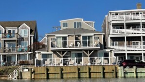A waterfront property with multiple balconies, a wooden dock, and a view of the water.