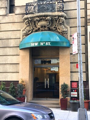 A building with a blue awning and a sign reading "38 W 31st St." - Macy Empire Apartments (New York)